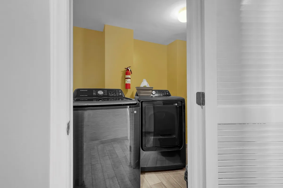 A compact laundry area featuring a washer and dryer, along with a fire extinguisher for safety. The setup is clean and practical, emphasizing easy access for guests to manage laundry during their stay.